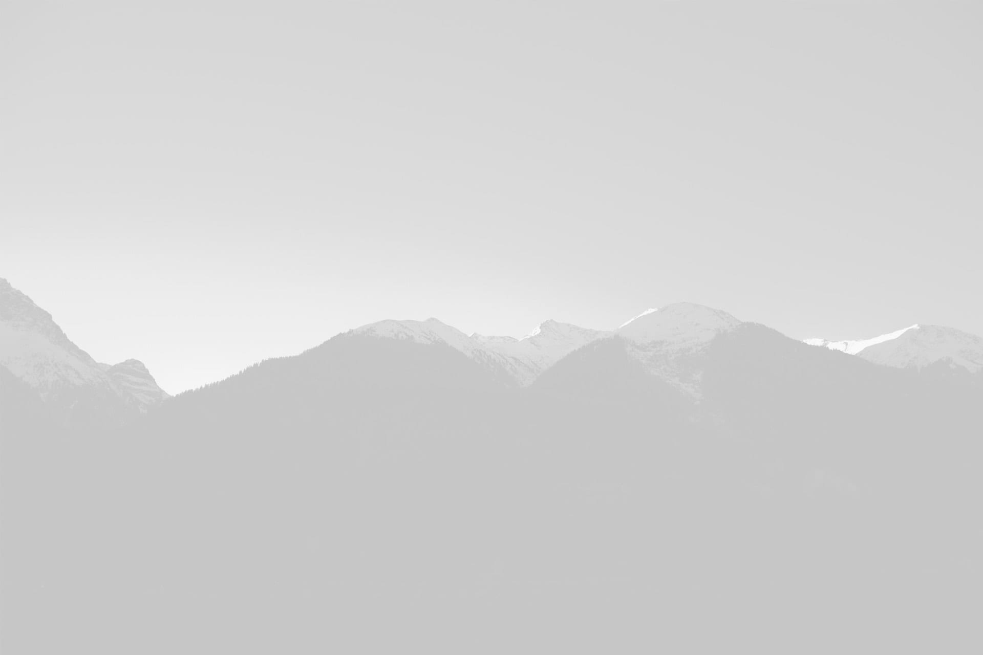 Black and white image of layered mountain silhouettes with misty gradients, showcasing depth and serene natural beauty.