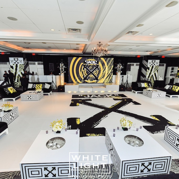 Elegant event space decorated in black and white theme, featuring tables with floral centerpieces and a large 
