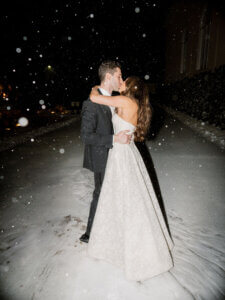 A wedding couple kissing in the snow.